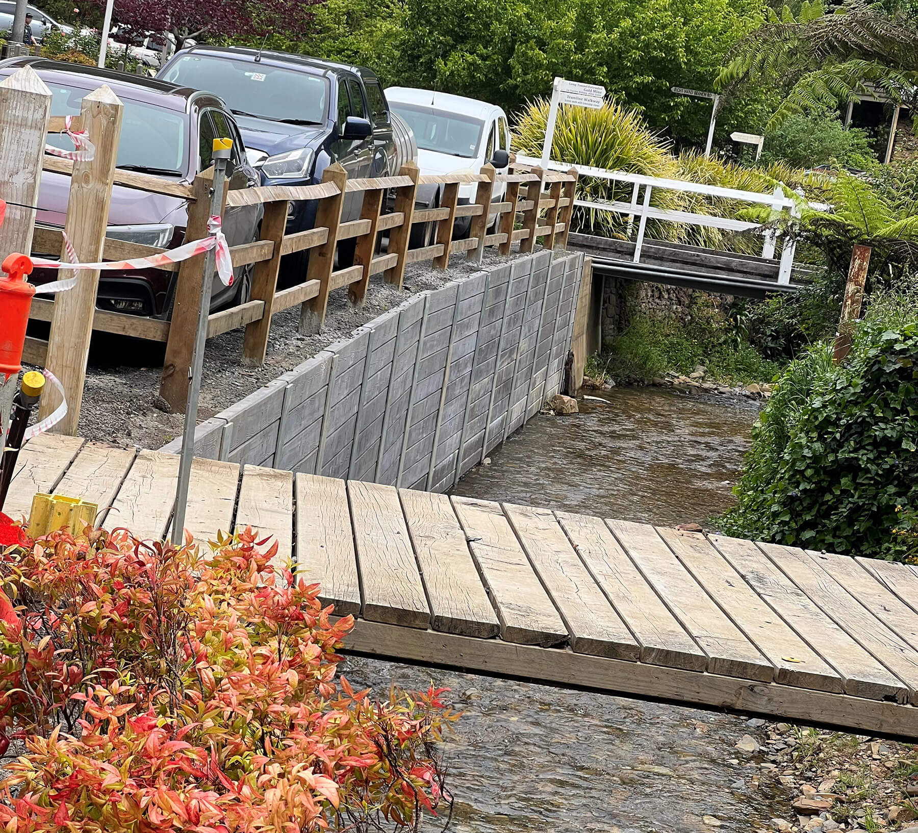 Photo looking along a small waterway with tall retaining walls on the sides, and cars parked along it.